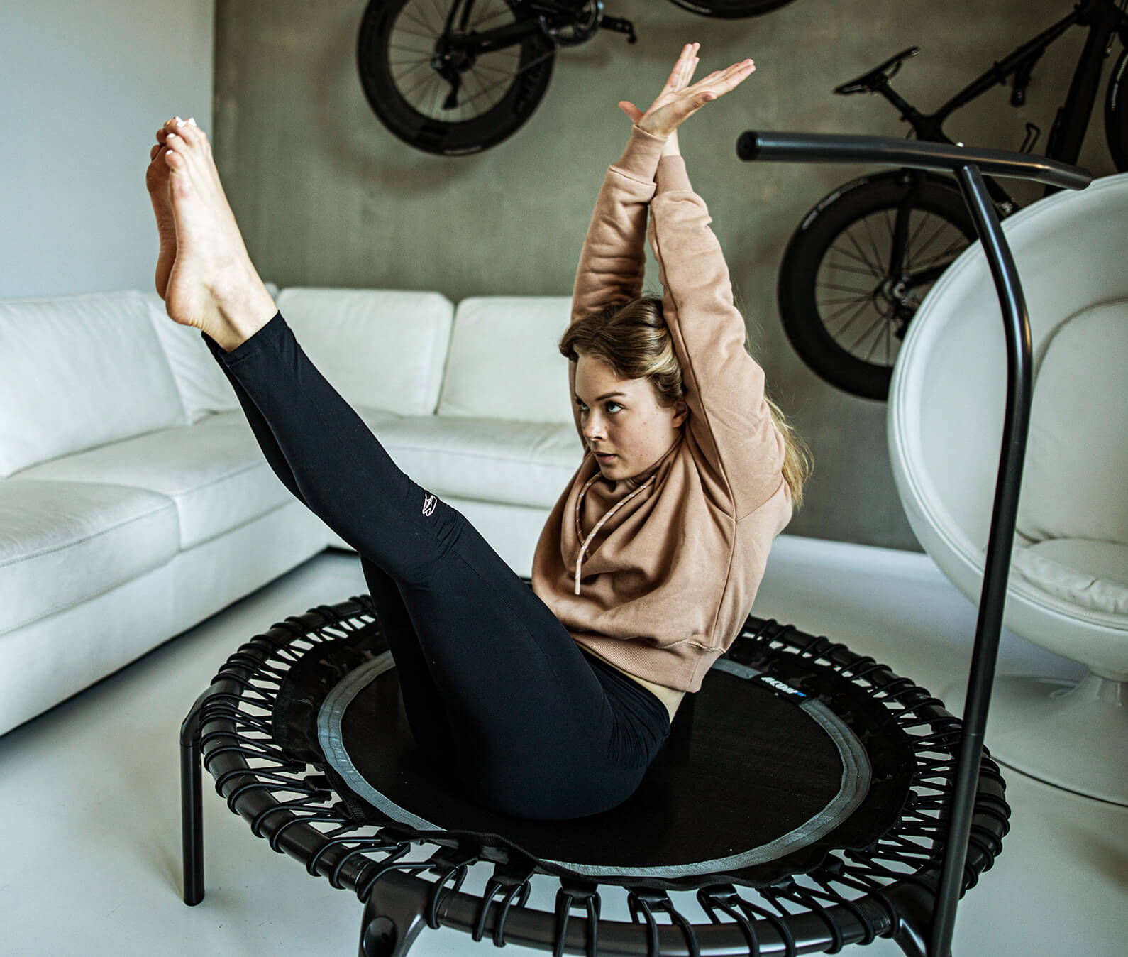 Nainen tekee linkkuveitsi -vatsalihasliikettä fitness trampoliinilla olohuoneessaan.