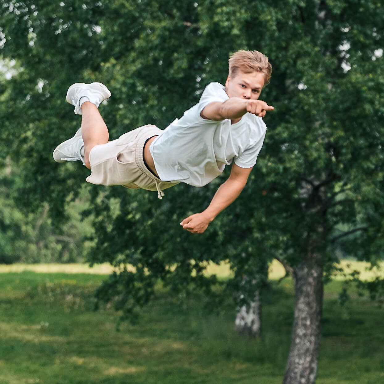Poika lentää ilmassa osoittaen sormellaan.
