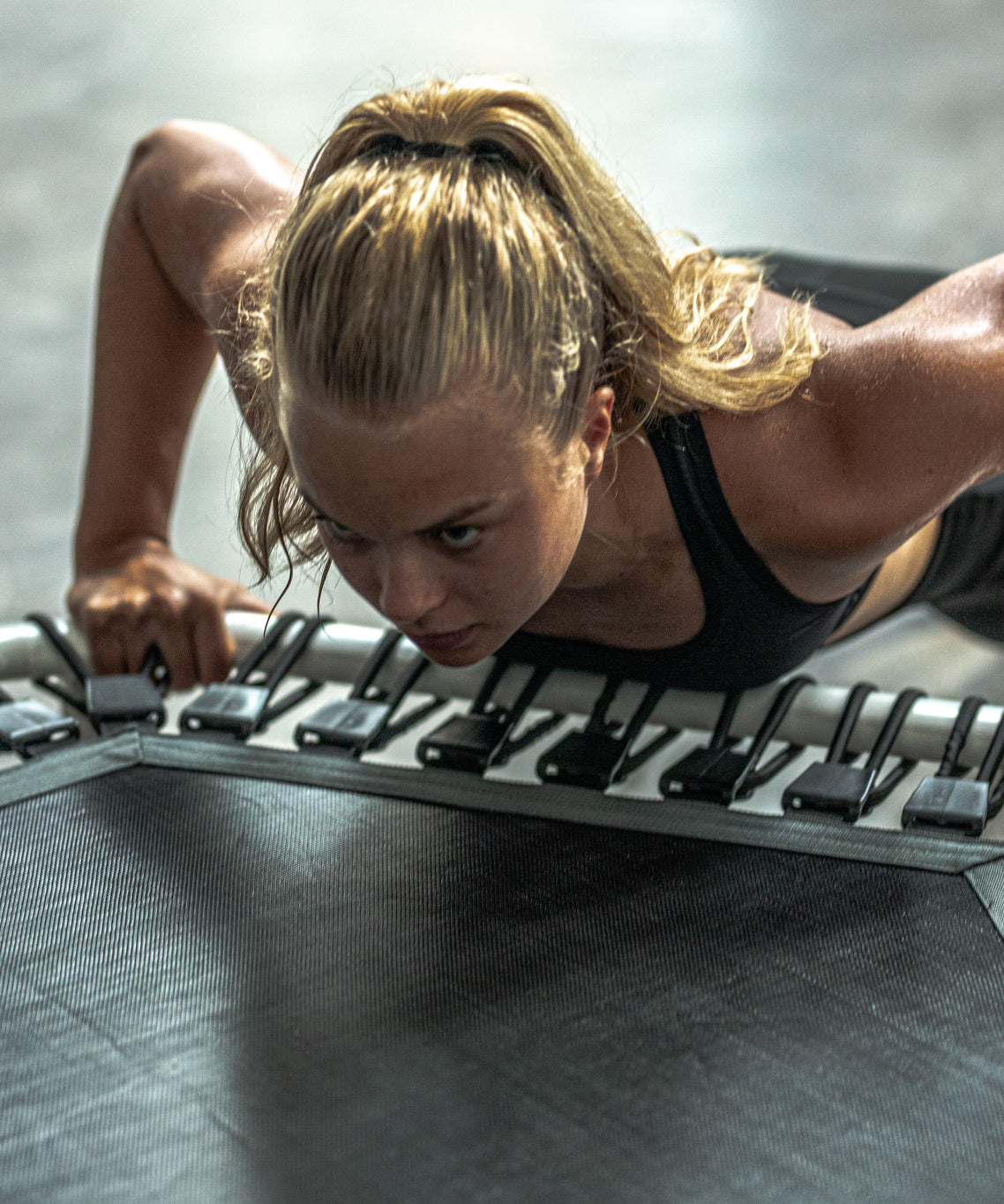 Nainen tekee etunojapunnerrusta fitness-trampoliinia vasten
