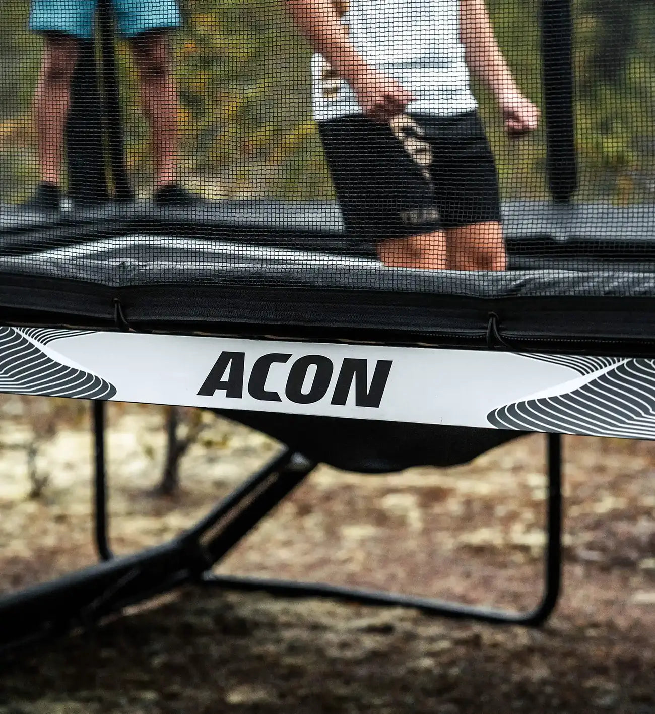 Hyppääjän jalat Acon X trampoliinilla, hypyn laskeutumisvaiheessa.