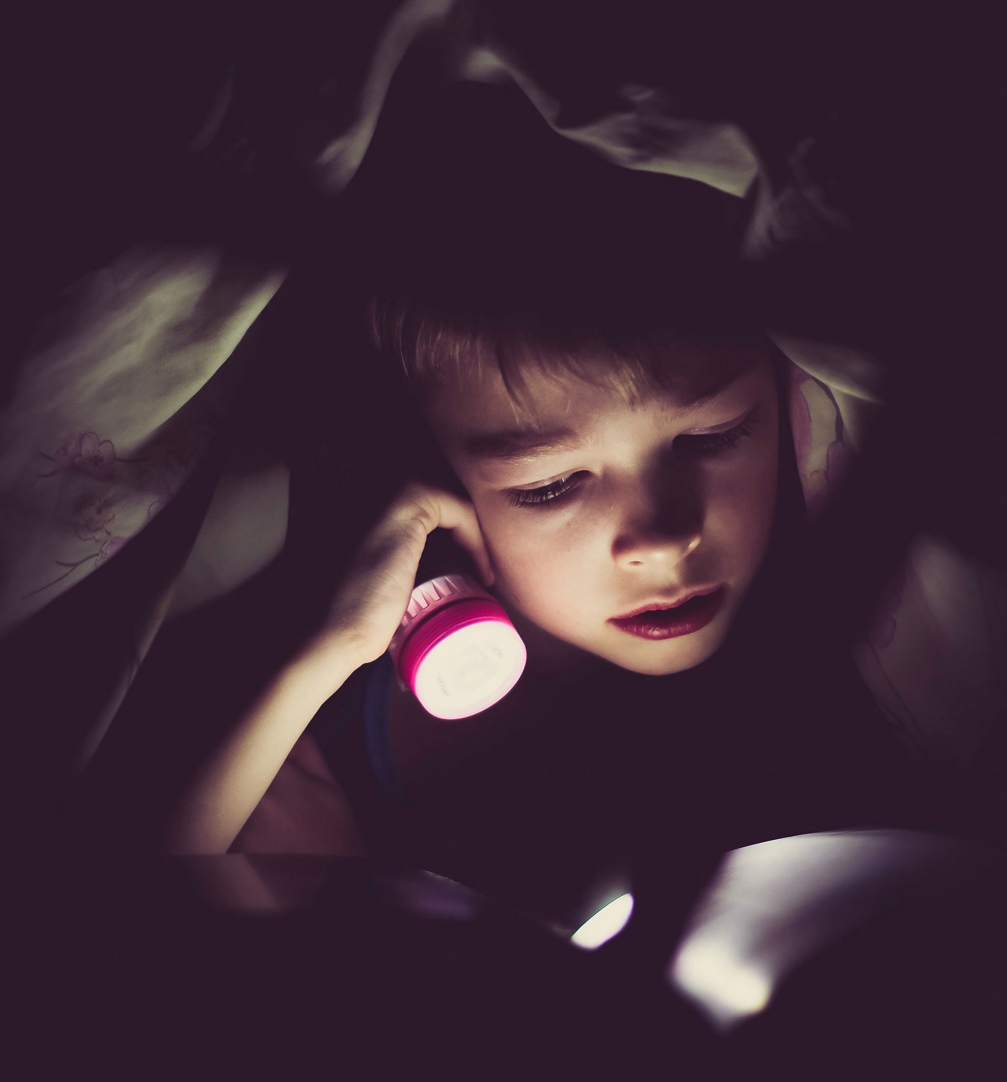 Lapsi teltassa lukee taskulampun valossa