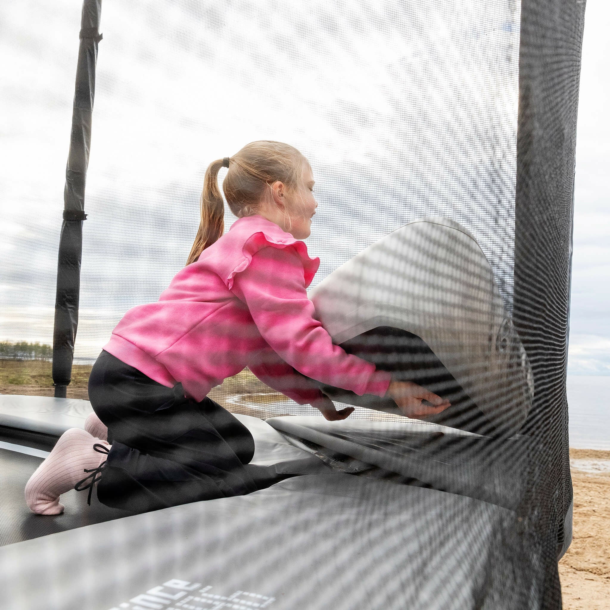 Tyttö asettaa puhallettavan Triangle Block -blokin Acon X -trampoliinille.