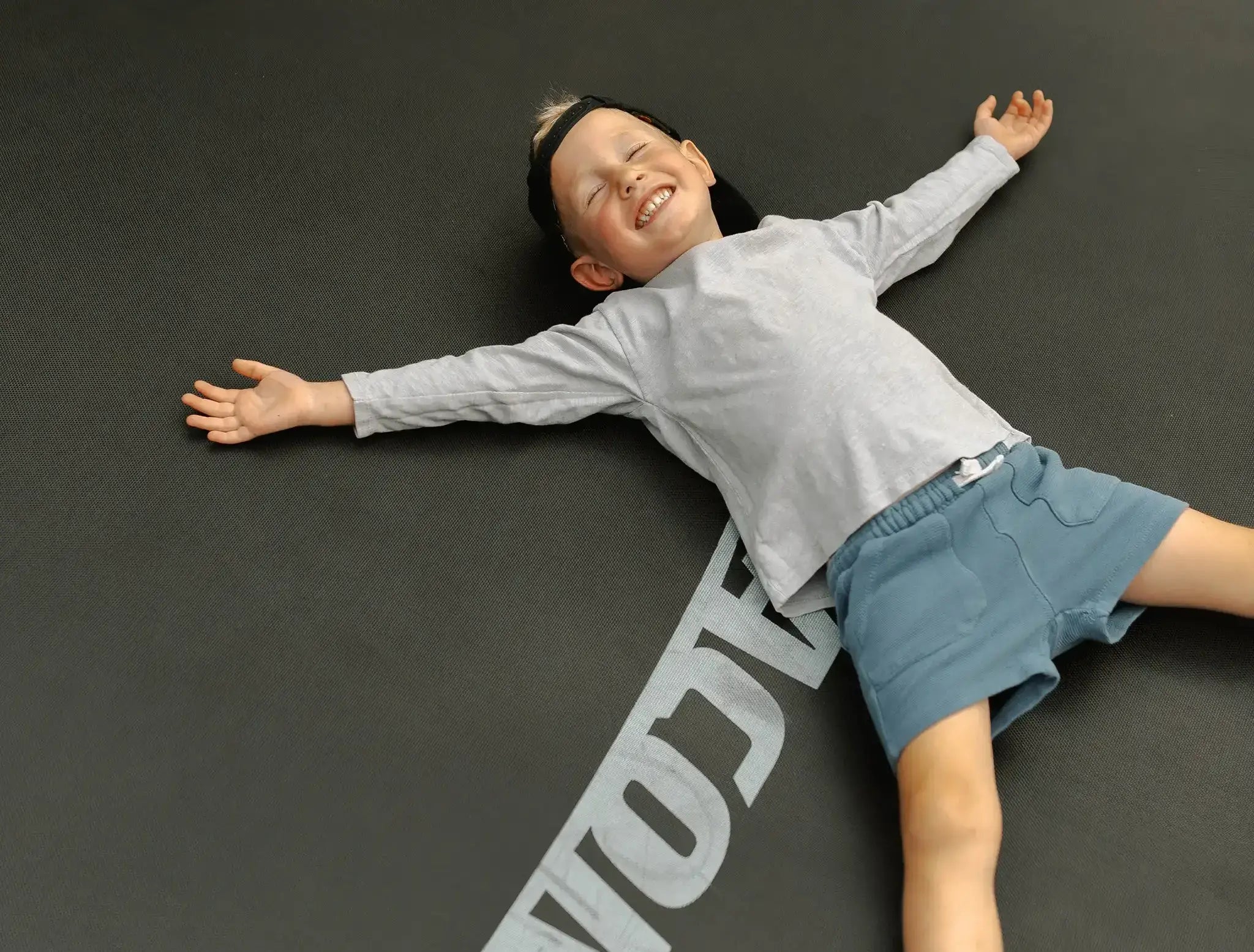 Iloinen lapsi makaa Acon-trampoliinilla.