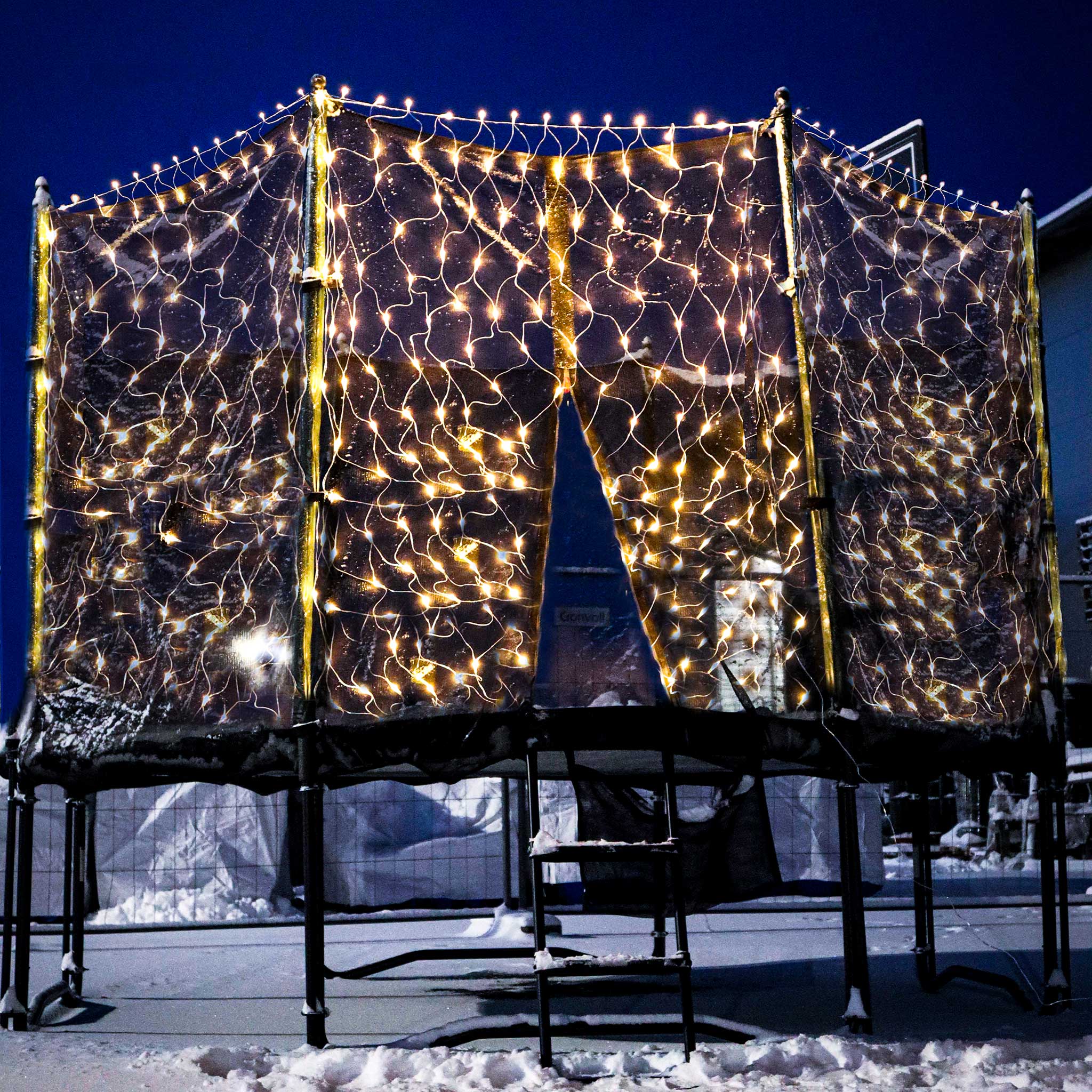 Jouluvaloin koristeltu trampoliini talvi-illassa