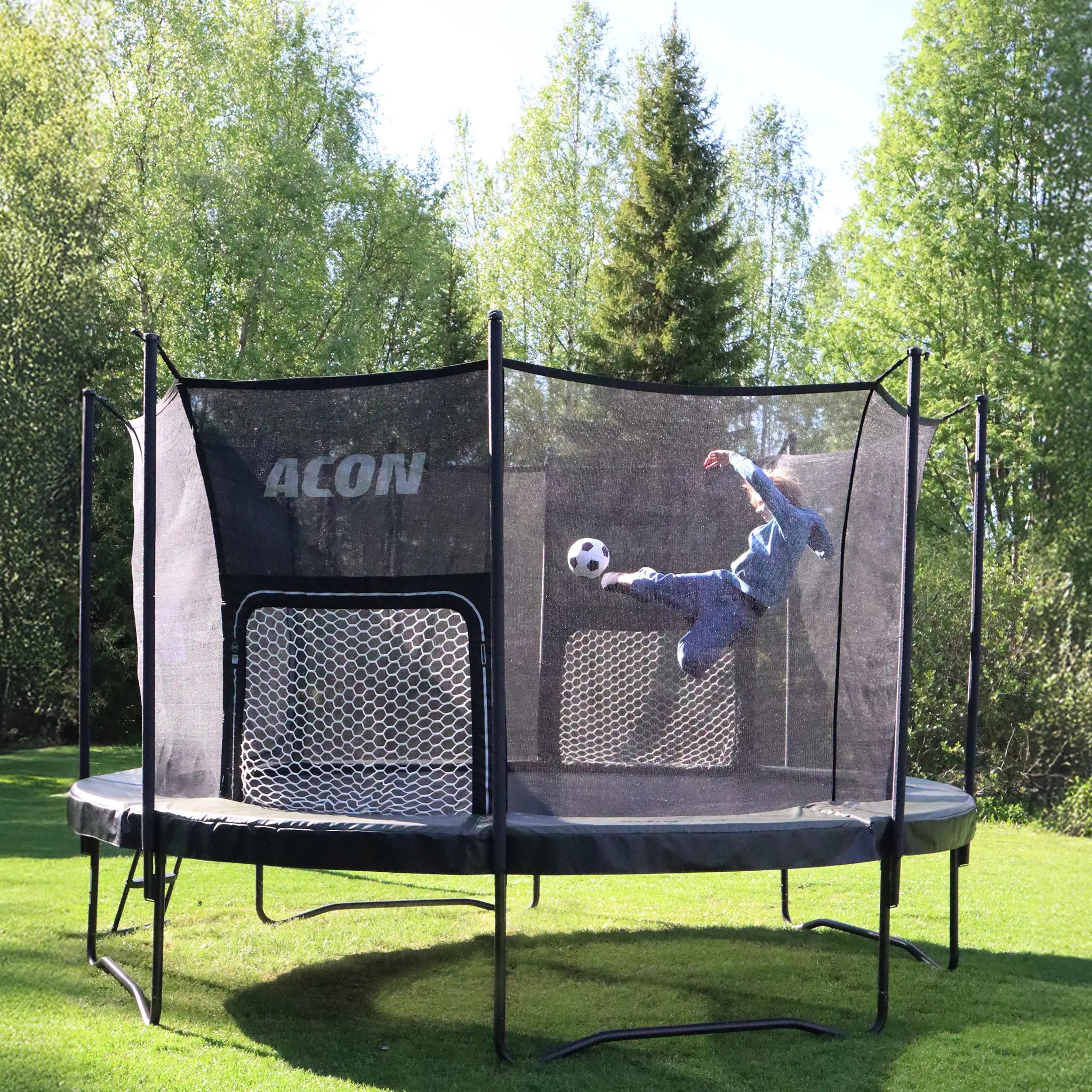 Lapsi potkaisemassa palloa kohti ACON Air Jalkapallomaalia ACON Air pyöreässä trampoliinissa.