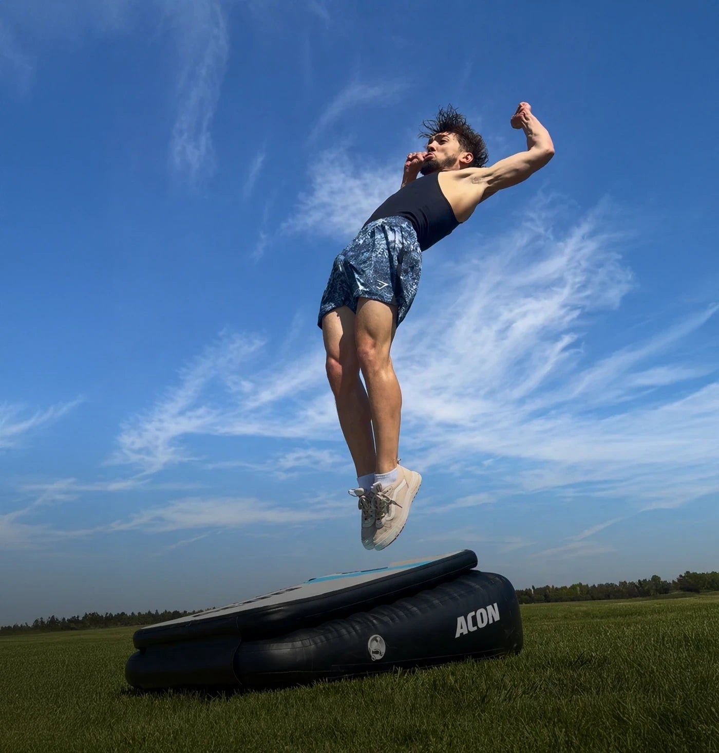 Mies hyppää Backflip Launchin Acon Airboardilla ulkona, Airboard nurmikolla.