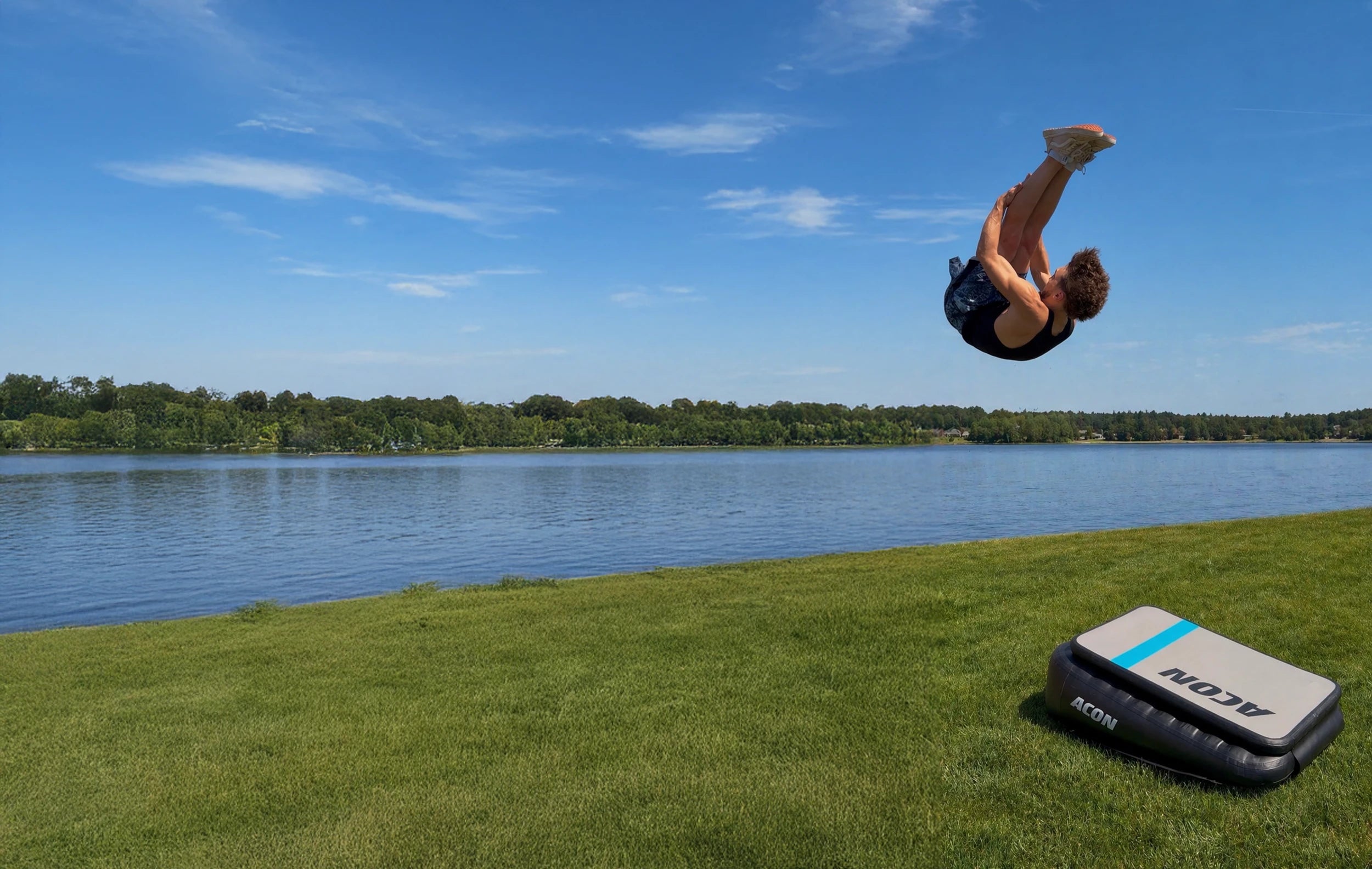 Mies hyppää Pike Frontin Acon Airboardilla joen rannassa, Airboard nurmikolla.