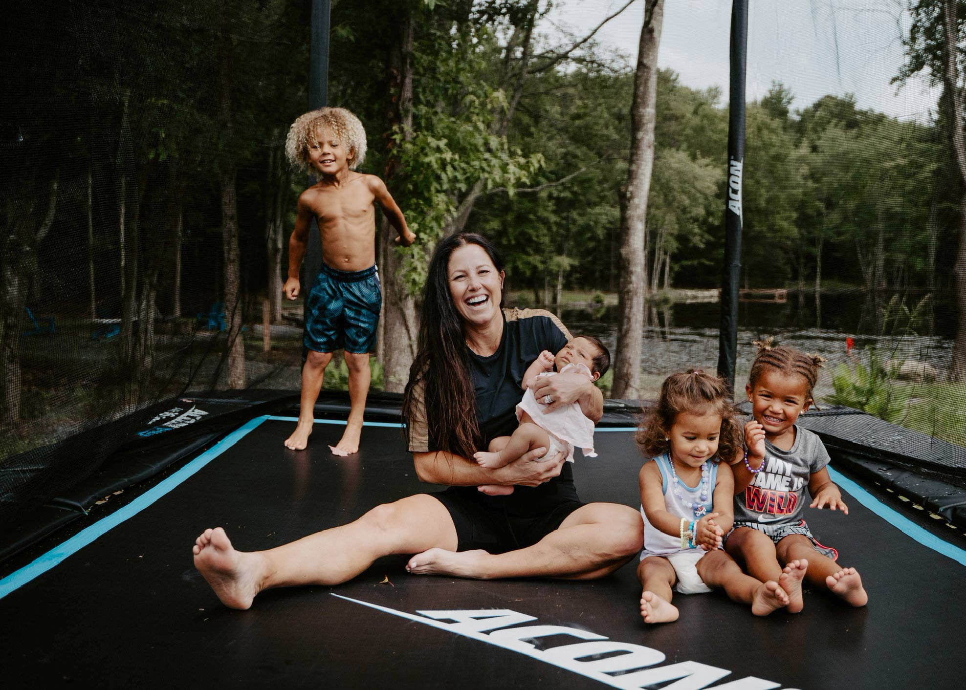 Äiti istuu neljän lapsen kanssa Acon HD -trampoliinilla