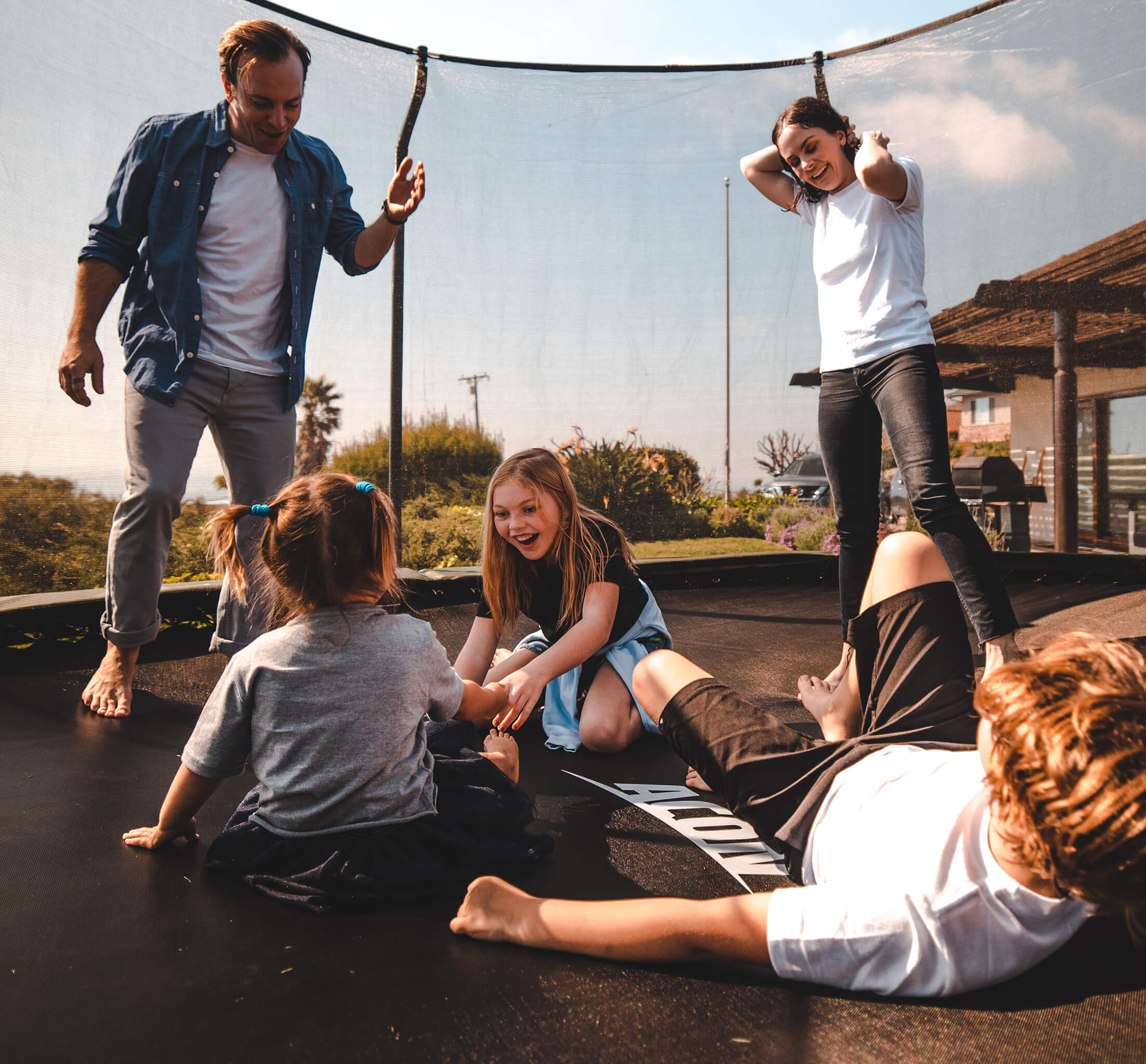 Isä, äiti ja kolme lasta telmivät Acon-trampoliinin päällä.