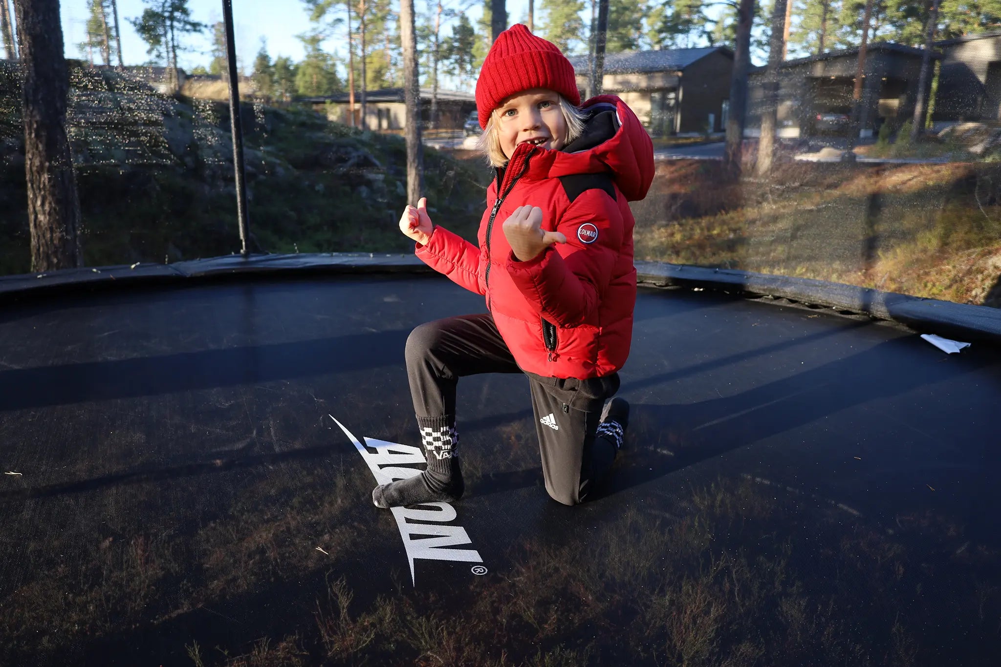 Iloinen lapsi talvi vaatteissa Aconin pyöreällä trampoliinilla. 