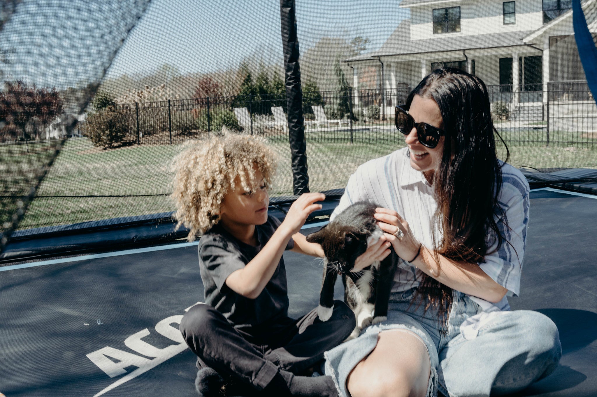 Äiti ja poika kissan kanssa ACON trampoliinilla