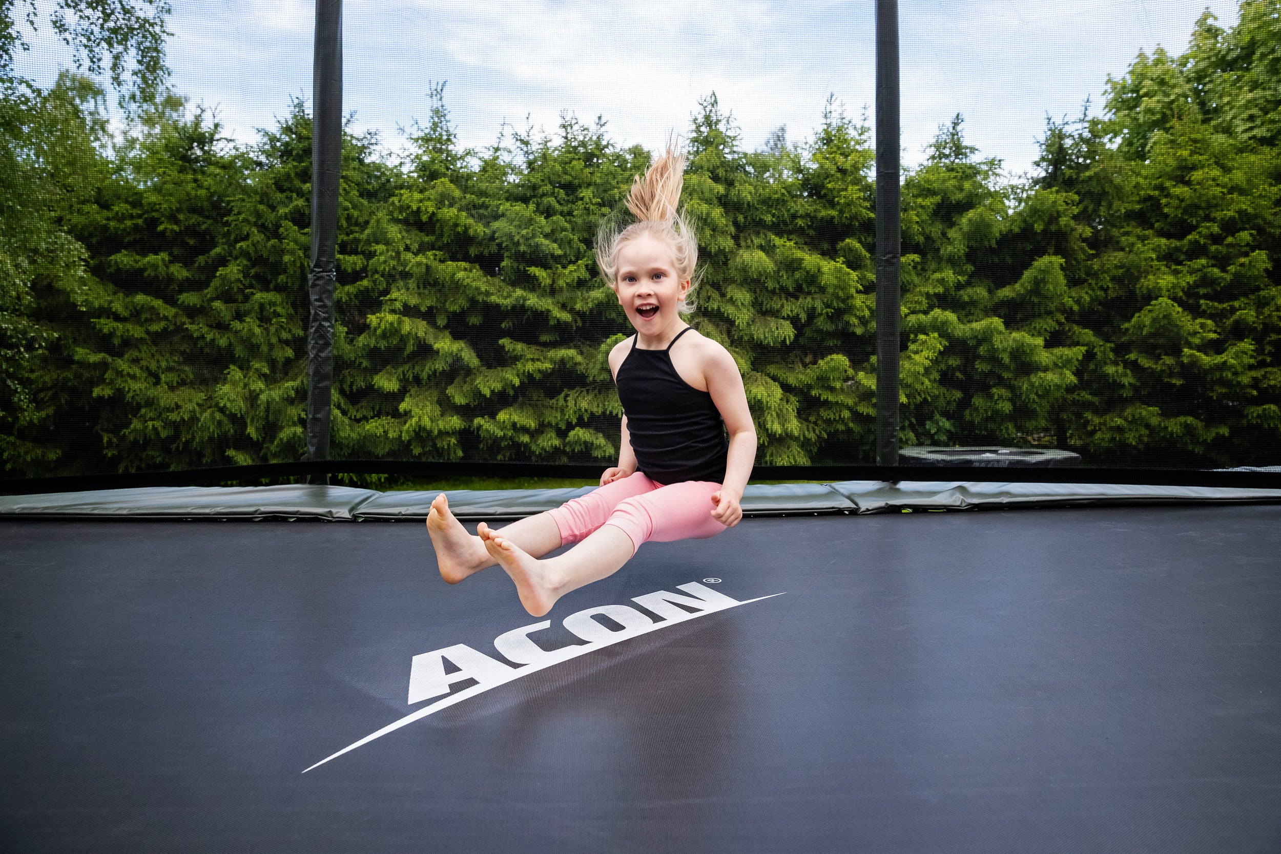 Pieni-lapsi-hyppii-trampoliinilla-laskeutuen-istualteen-trampoliinimatolle