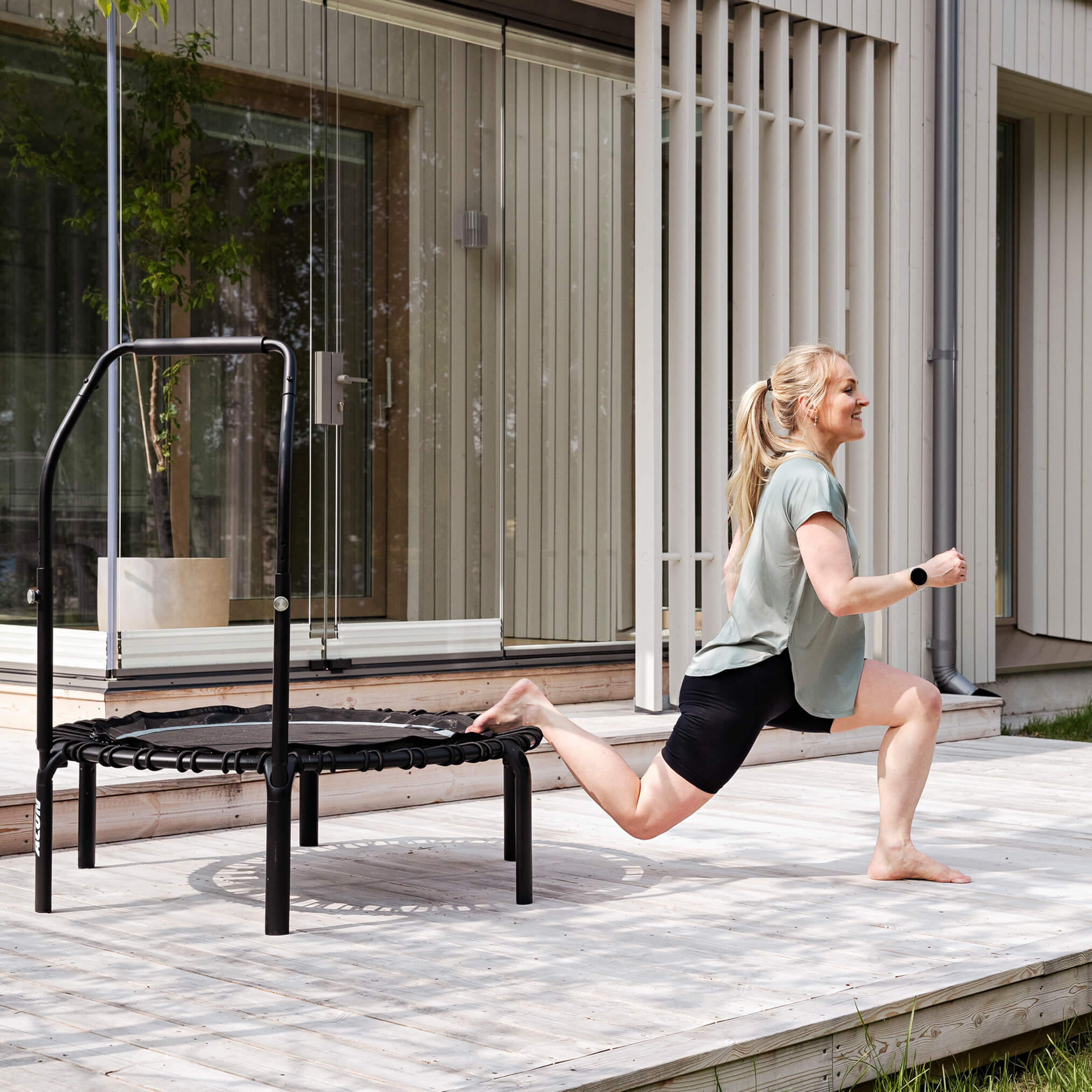 Nainen tekee taivutuksia Acon FIT Balance rebounderilla talon terassilla.