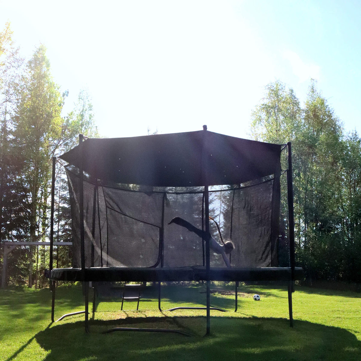 Acon Air pyöreä trampoliini aurinkosuojalla aurinkoisessa ulkoympäristössä, lapsi hyppää.