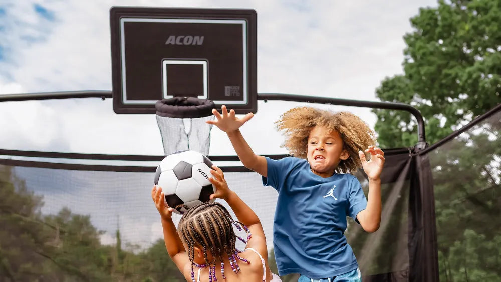 Lapset pelaavat ACON Basketball Hoop -koripallokorin kanssa Acon X -trampoliinilla.