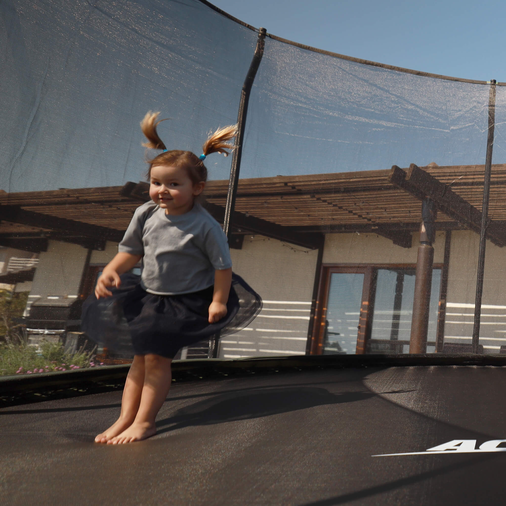 Pieni lapsi hyppää Acon-trampoliinilla.