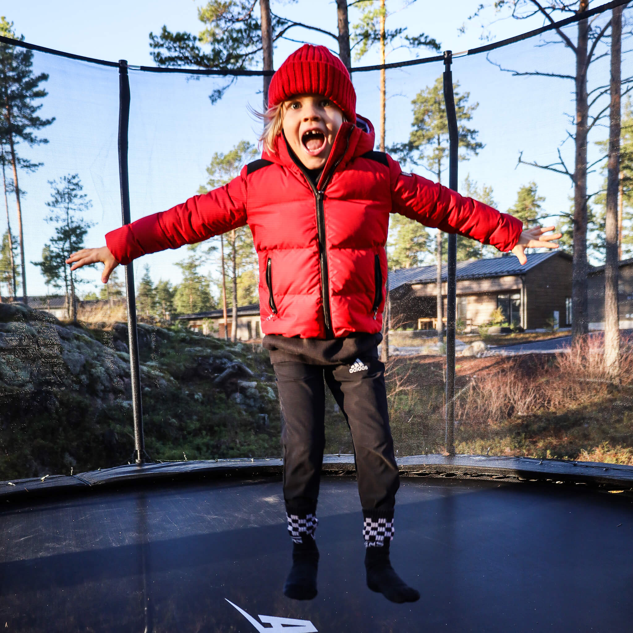 Punatakkinen tyttö hyppää Acon-trampoliinilla.