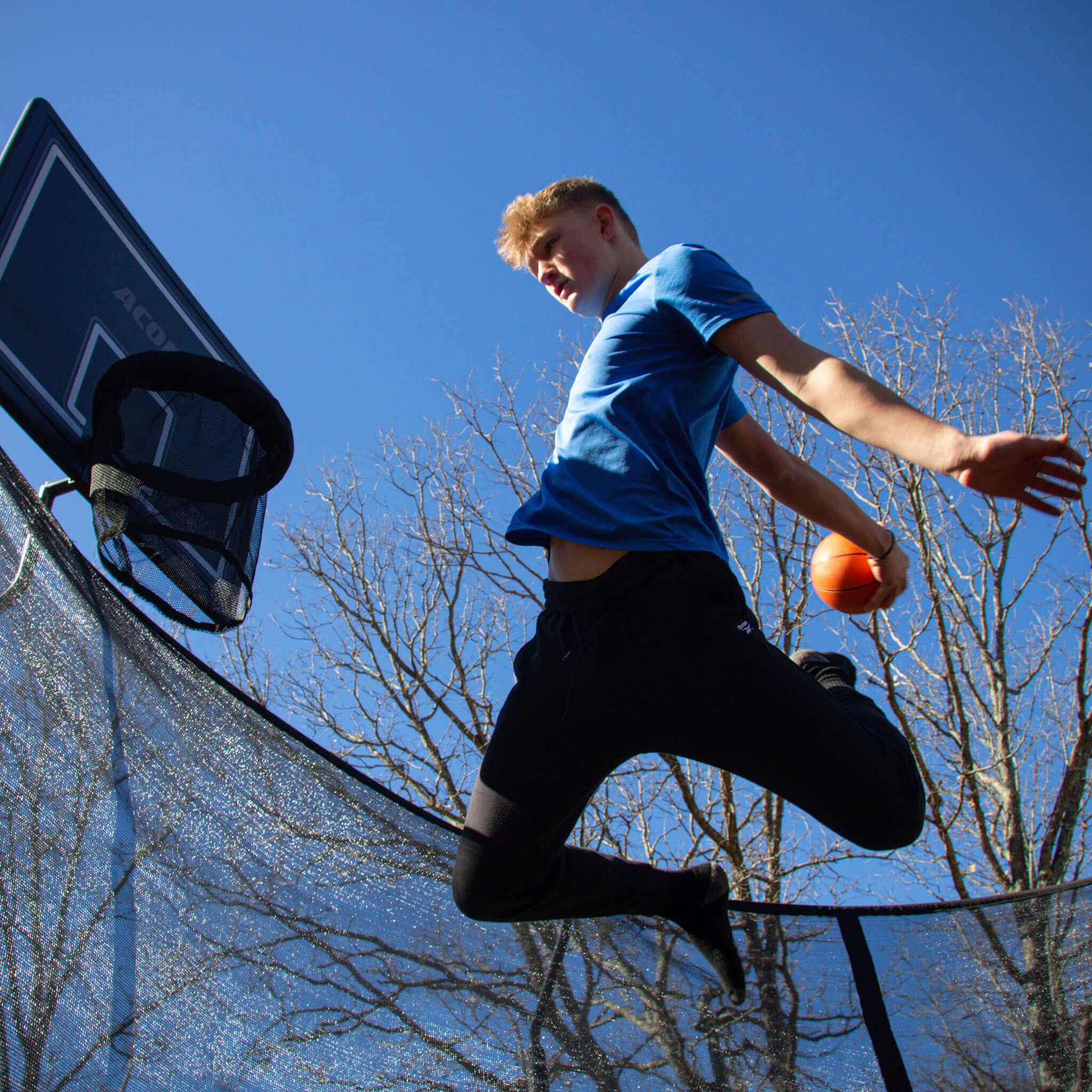 Koripallon pelaaja pyöreällä trampoliinilla.